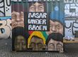 Container som opbevarer borde og tøjstativer for basaren under broen malet med graffitti seks ansigter og navnet på basaren.